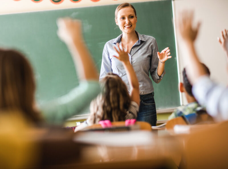 Lachende weibliche Lehrerin befragt ihre Klasse