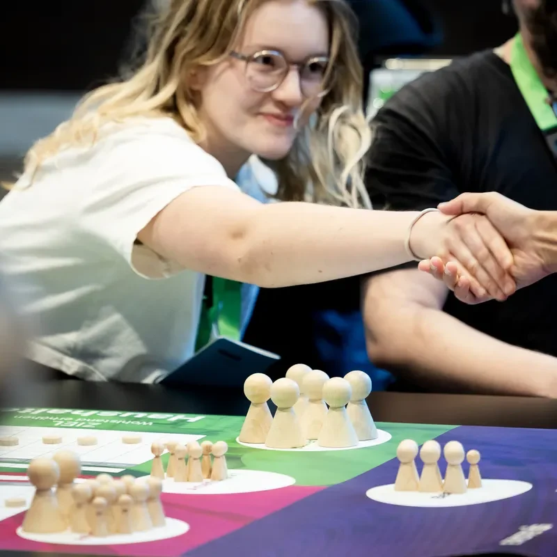 Personen reichen sich die Hand am Spieltisch