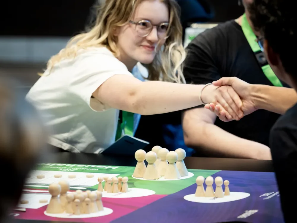 Personen reichen sich die Hand am Spieltisch