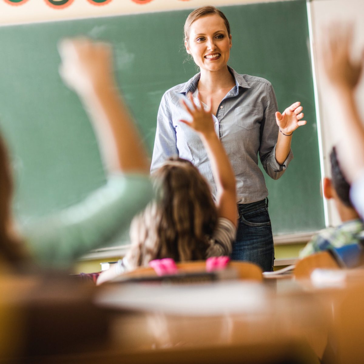 Lachende weibliche Lehrerin befragt ihre Klasse